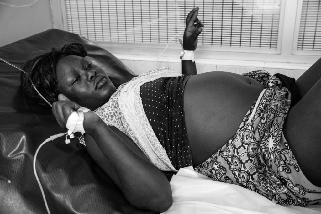 Pregnant woman lies down on hospital bed receiving IV fluid