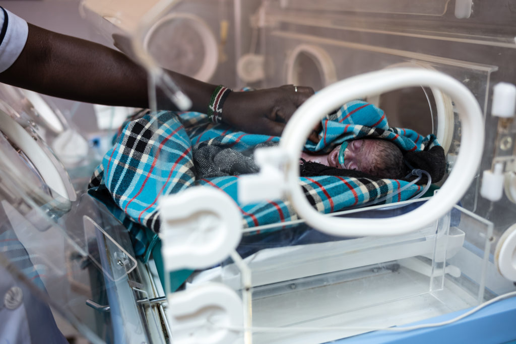Medical adjusts blanket of baby in ICU